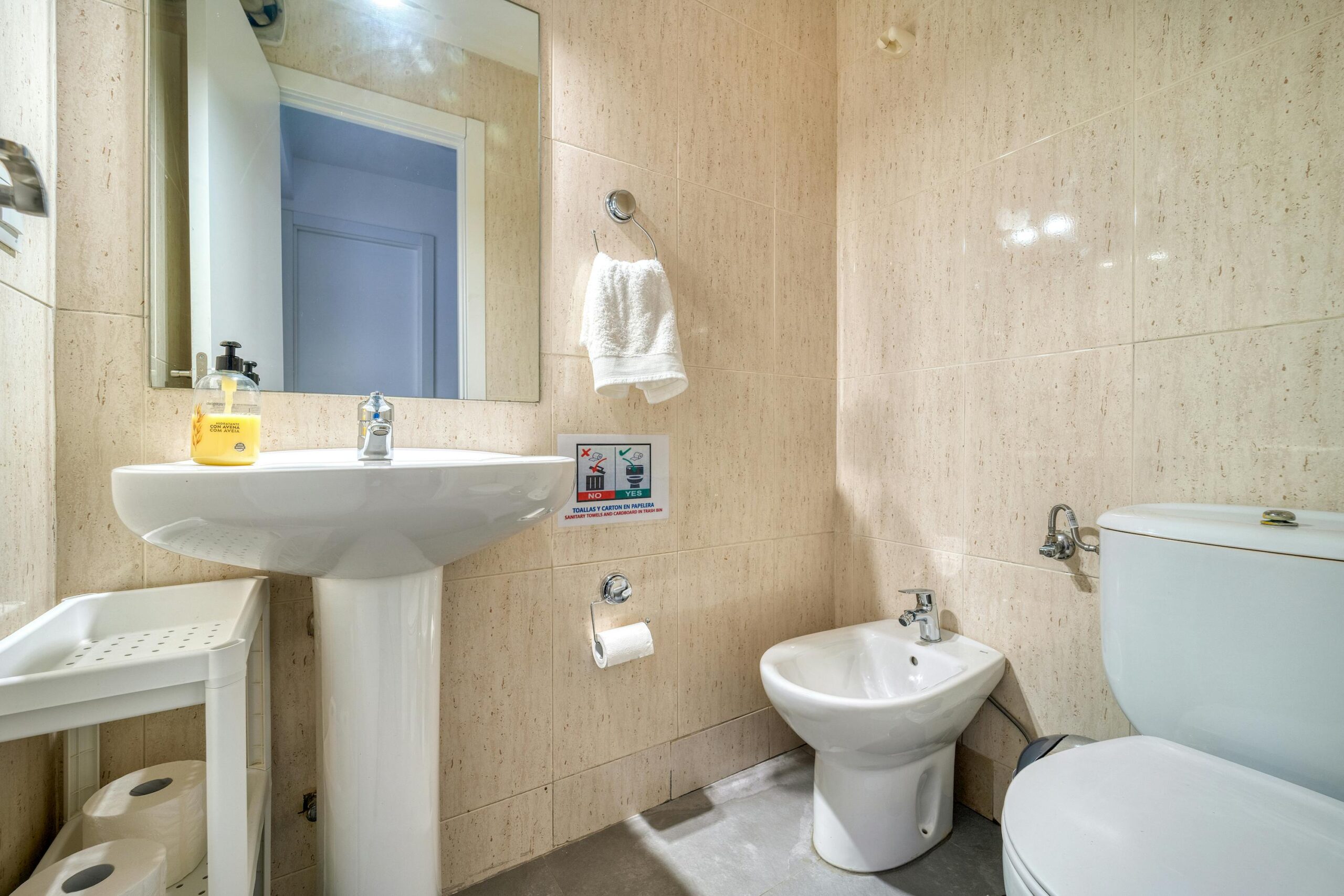 Elegant bathroom interior featuring a pedestal sink, bidet, and neutral tiles.